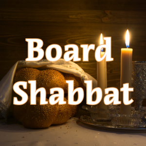 A candle and a loaf of challah in the background; Board Shabbat in the foreground.